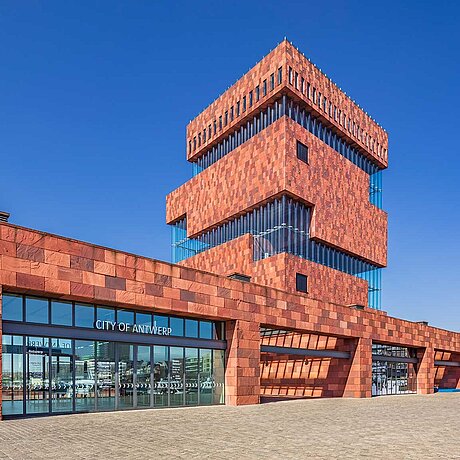 Edificio moderno con facciata in pietra rossa.
