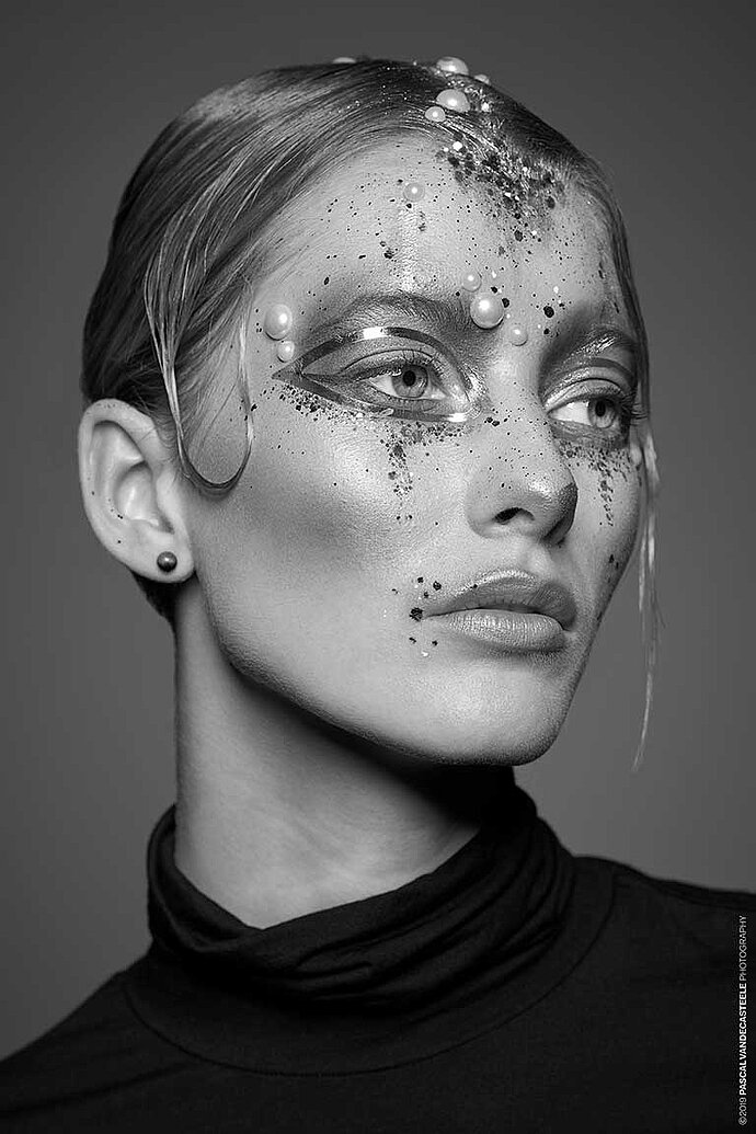 Portret van een model met glitter en parels op haar gezicht.