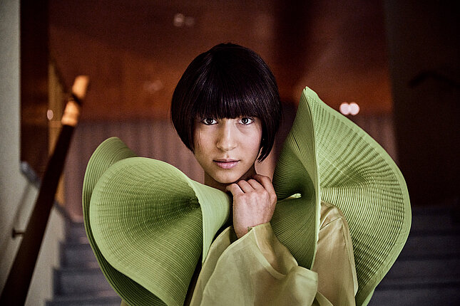 Portrait d'une danseuse avec un col vert futuriste sur sa robe.