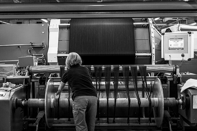 [Translate to Swiss English:] Woman working at the weaving machine.